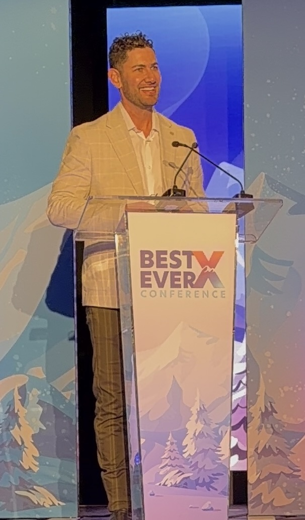 Ben Kogut speaking on stage at the Best Ever X Conference